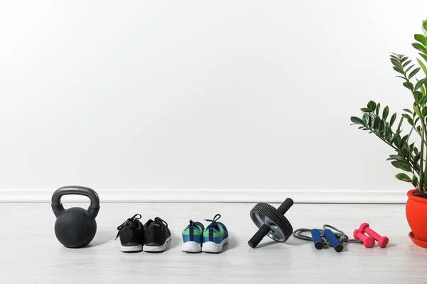 Спортивная обувь, скакалка, колесо живота и гири на полу дома — стоковое фото