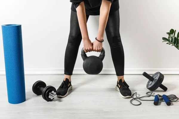 Vista cortada de treinamento esportivo com kettlebell em casa com material esportivo — Fotografia de Stock