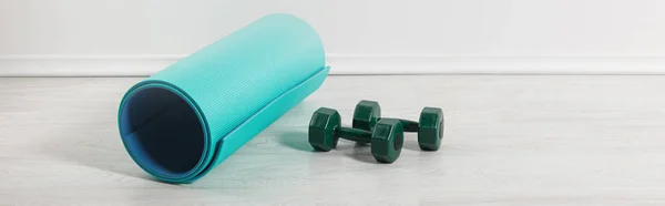 Panoramic shot of blue fitness mat and dumbbells on floor at home — Stock Photo