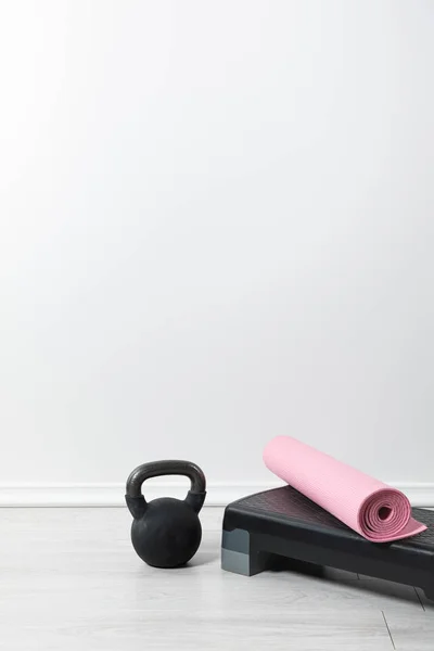 Step platform, kettlebell and pink fitness mat on floor at home — Stock Photo