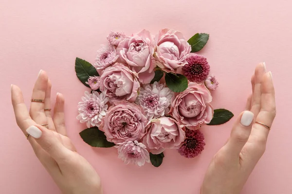 Top view of blooming spring flowers and female hands on pink background — Stock Photo