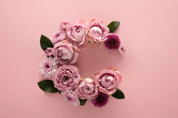 Vista superior de flores florecientes de primavera dispuestas como letra C sobre fondo rosa - foto de stock