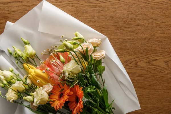 Vue de dessus du bouquet de printemps coloré en fleurs sur papier sur fond en bois — Photo de stock