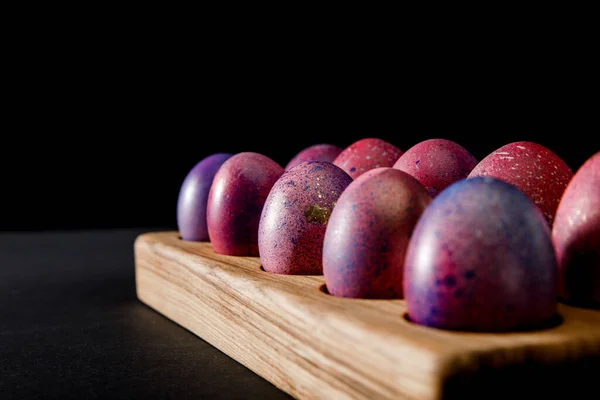 Focus selettivo di uova di Pasqua colorate su tavola di legno su sfondo grigio e nero — Foto stock