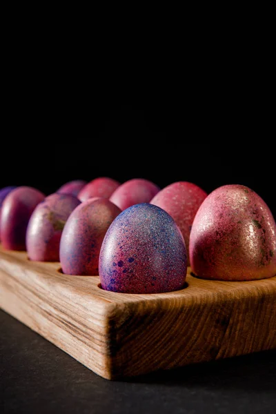 Selective focus of Easter eggs on wooden board on black — Stock Photo