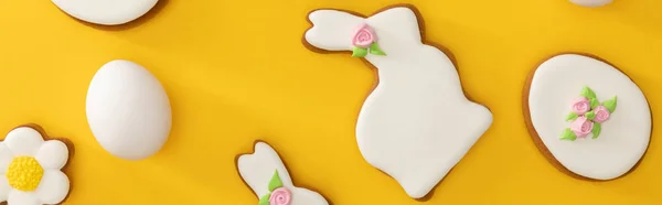 Vista superior de las deliciosas galletas de Pascua y huevo de gallina sobre fondo amarillo, plano panorámico - foto de stock