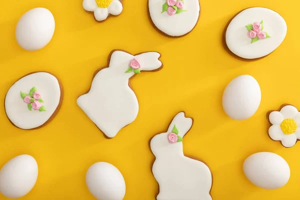 Vista superior de saborosos biscoitos de Páscoa e ovos de galinha no fundo amarelo — Fotografia de Stock