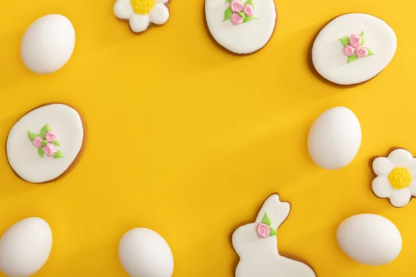 Vue de dessus des biscuits de Pâques savoureux et des œufs de poulet sur jaune — Photo de stock