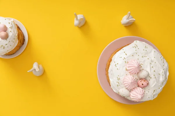 Vue du dessus des gâteaux de Pâques avec des lapins décoratifs sur fond jaune — Photo de stock