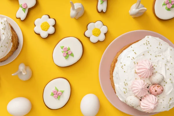 Vista dall'alto di torte pasquali, uova di pollo, biscotti e coniglietti decorativi su sfondo giallo — Foto stock