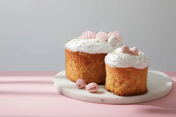 Delicious easter cakes and quail eggs on round board on grey and pink — Stock Photo