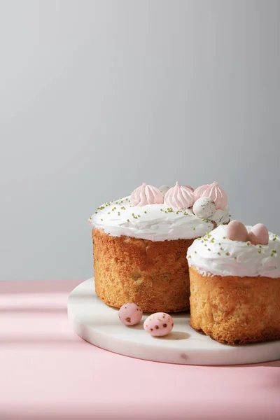 Delicious easter cakes and quail eggs on round board on grey background — Stock Photo