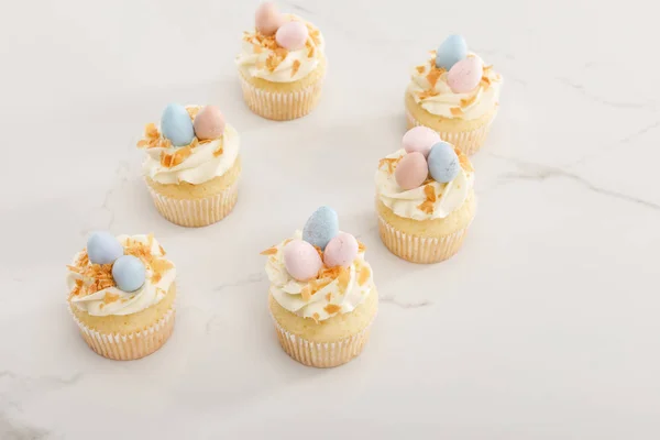 Deliciosos cupcakes de Pascua con coloridos huevos de codorniz en la parte superior sobre fondo blanco - foto de stock