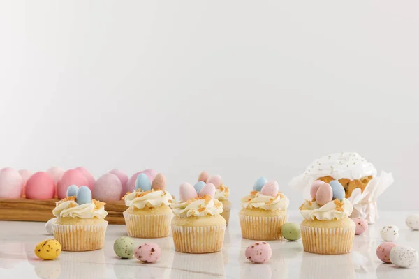 Delicious cupcakes with colorful painted chicken and quail eggs near easter cake isolated on grey — Stock Photo