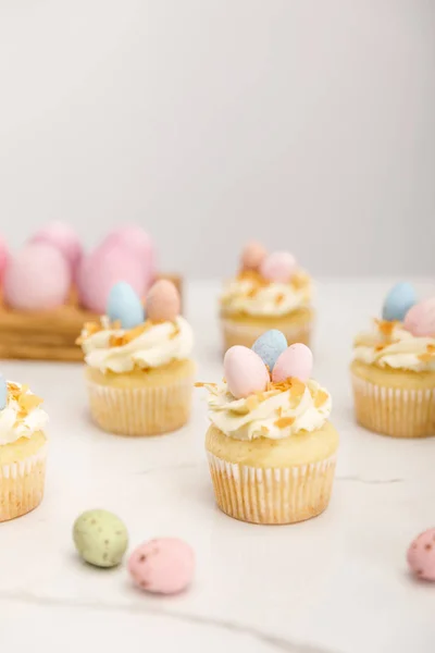 Enfoque selectivo de deliciosos cupcakes de Pascua con huevos de codorniz pintados sobre fondo gris - foto de stock
