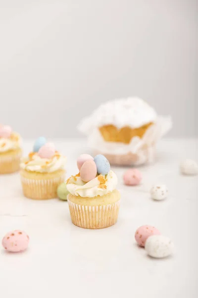 Focus selettivo di deliziosi cupcake con uova di quaglia dipinte e pane pasquale su sfondo grigio — Foto stock