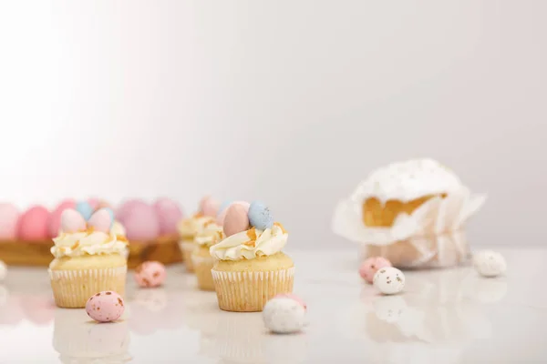 Enfoque selectivo de cupcakes con pollo pintado y huevos de codorniz cerca de pastel de Pascua sobre fondo gris - foto de stock