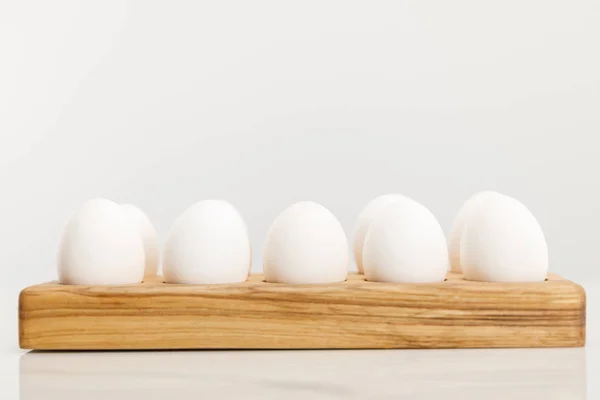 Wooden board with chicken eggs on white background — Stock Photo