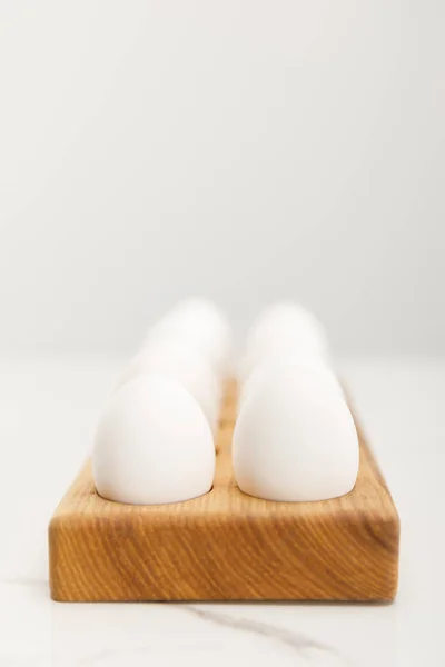Selective focus of wooden board with chicken eggs on grey background — Stock Photo