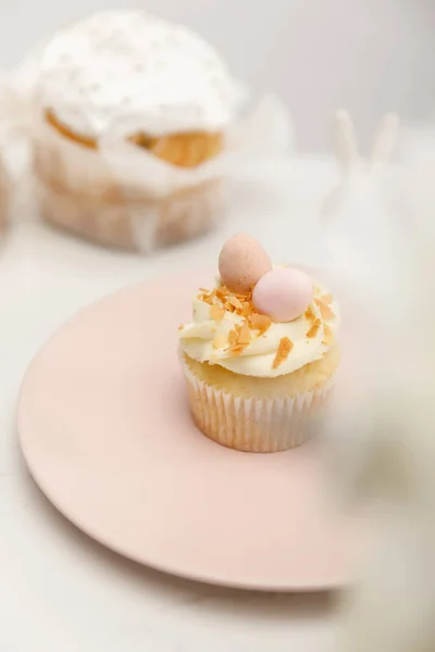 Focus selettivo di cupcake su piatto e torta di Pasqua su sfondo bianco — Foto stock