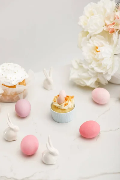 Cupcake com ovos de galinha coloridos, coelhos decorativos, bolos de Páscoa e flores em fundo branco — Fotografia de Stock