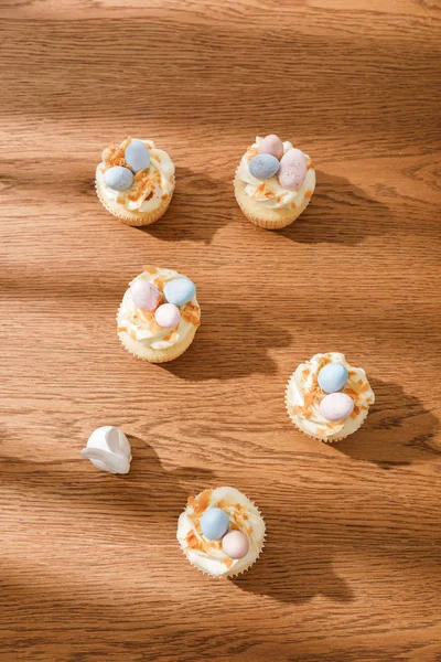 Top view of delicious cupcakes with decorative bunny on wooden background — Stockfoto