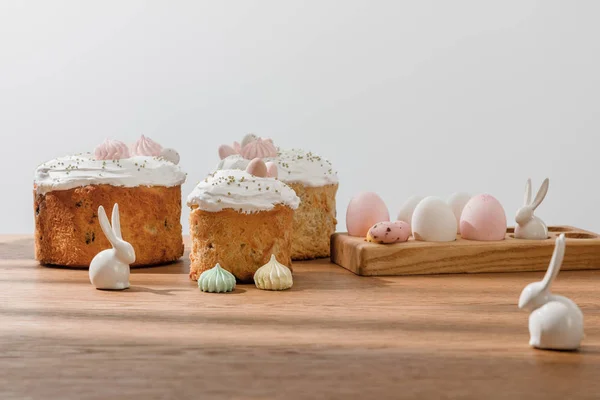 Decorative bunnies, chicken and quail eggs on egg tray, meringues near Easter cakes isolated on grey — Stock Photo