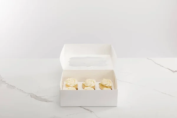 Tasty cupcakes in box isolated on grey — Stock Photo