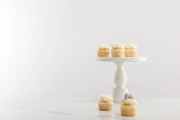 Tasty easter cupcakes on cake stand isolated on grey — Stock Photo