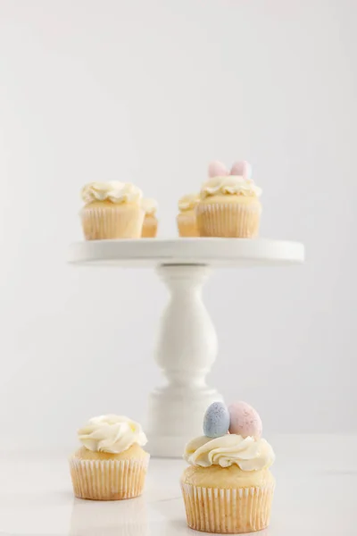 Mise au point sélective de délicieux cupcakes sur support de gâteau isolé sur gris — Photo de stock
