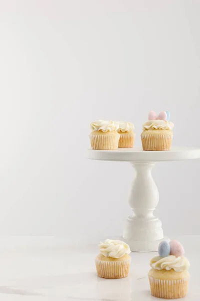 Enfoque selectivo de cupcakes en soporte de pastel aislado en gris - foto de stock