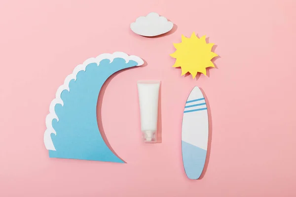Vista superior do sol de corte de papel, nuvem, onda do mar e prancha de surf com tubo de protetor solar sobre fundo rosa — Fotografia de Stock
