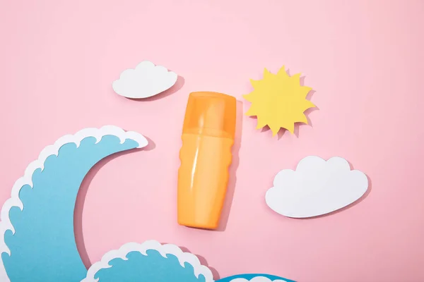 Vue du dessus de la plage de papier découpé avec flacon distributeur de crème solaire sur fond rose — Photo de stock