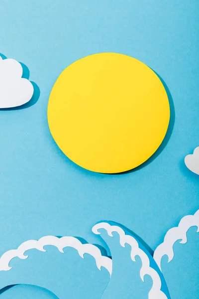 Draufsicht auf Papier geschnittene Sonne, Wolken und Meereswellen auf blauem Hintergrund — Stockfoto