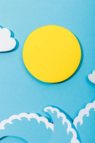 Vue du dessus du papier coupé soleil, nuages et vagues de mer sur fond bleu — Photo de stock