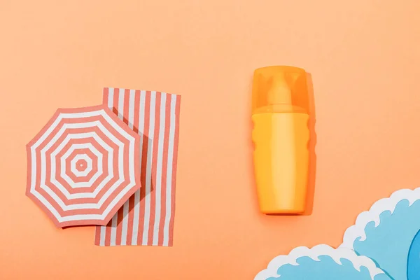 Vue du dessus de la bouteille distributeur de crème solaire avec du papier coupé vagues de mer sur fond orange — Photo de stock