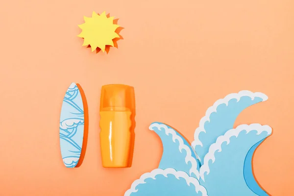 Top view of dispenser bottle of sunscreen with paper cut sea waves, sun and surfboard on orange — Stock Photo