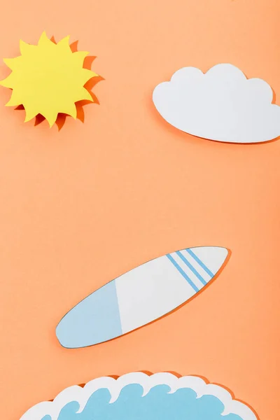 Vue du dessus du papier coupé soleil, nuage, planche de surf et vague de mer sur fond orange — Photo de stock