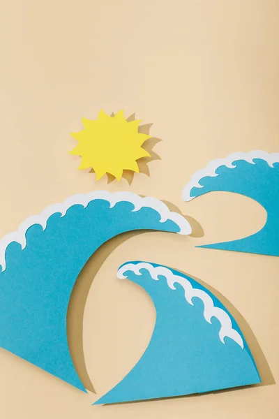 Vista superior do sol de corte de papel e ondas azuis do mar em bege — Fotografia de Stock
