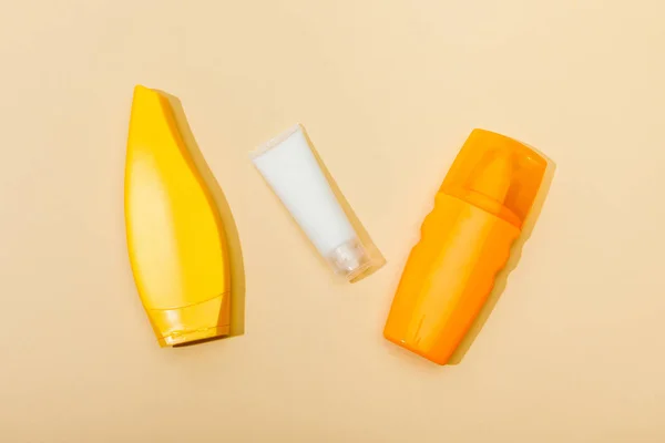 Top view of tubes and dispenser bottle of sunscreen on beige background — Stock Photo