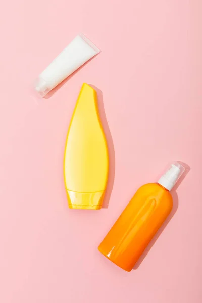 Top view of tubes and dispenser bottle of sunscreen on pink background — Stock Photo