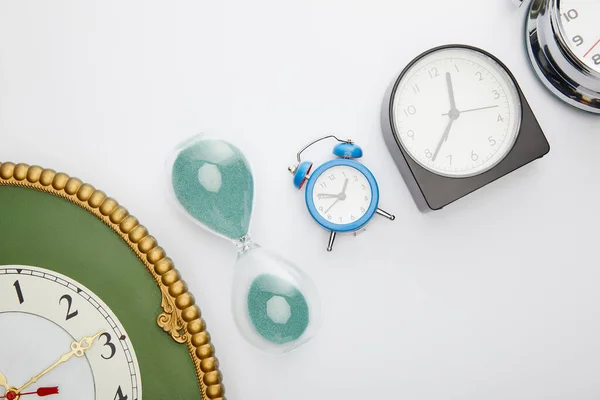 Plano con relojes de alarma clásicos y reloj de arena sobre fondo blanco - foto de stock