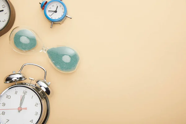 Top view of classic alarm clocks and hourglass on beige background — Stock Photo