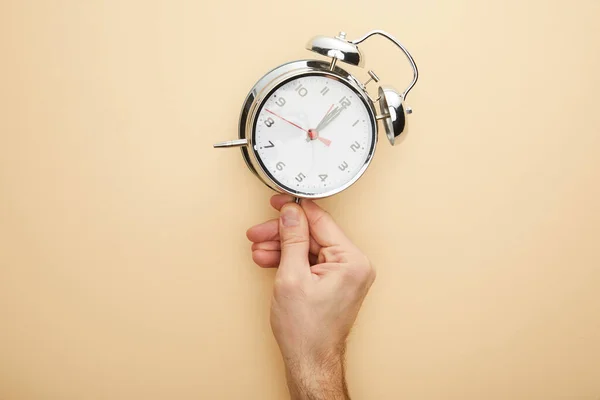 Cropped view of man touching classic alarm clock on beige background — Stock Photo