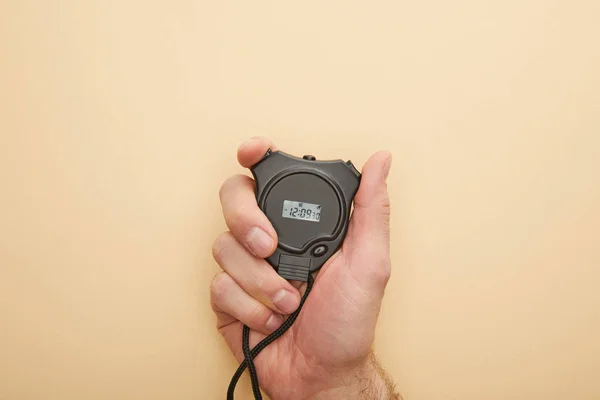 Cropped view of man holding stopwatch on beige background — Stock Photo