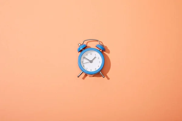 Vista superior del reloj despertador clásico sobre fondo melocotón - foto de stock