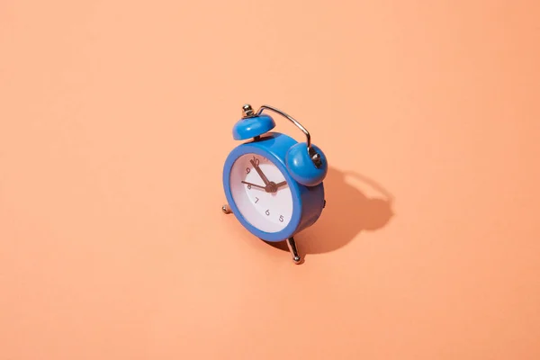 Small blue classic alarm clock on peach background — Stock Photo