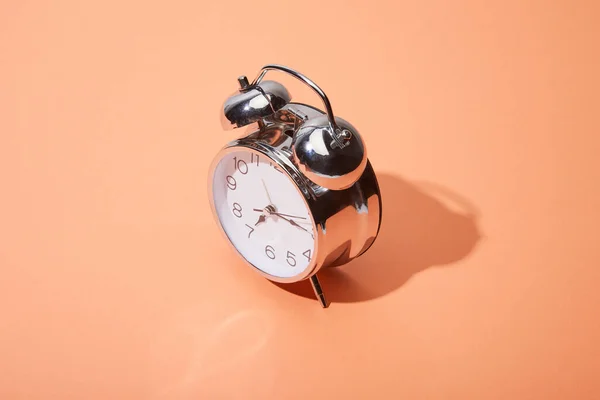 Reloj despertador clásico sobre fondo melocotón - foto de stock