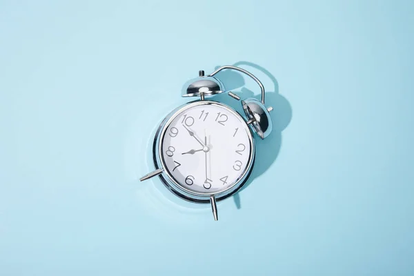 Vista superior del reloj despertador clásico sobre fondo azul - foto de stock