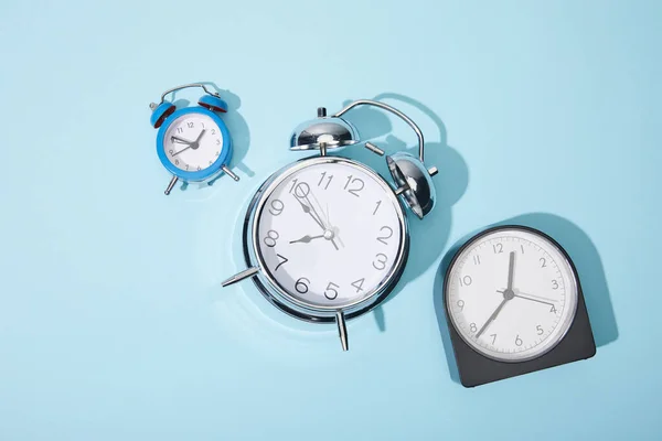 Vista superior de los relojes de alarma sobre fondo azul - foto de stock